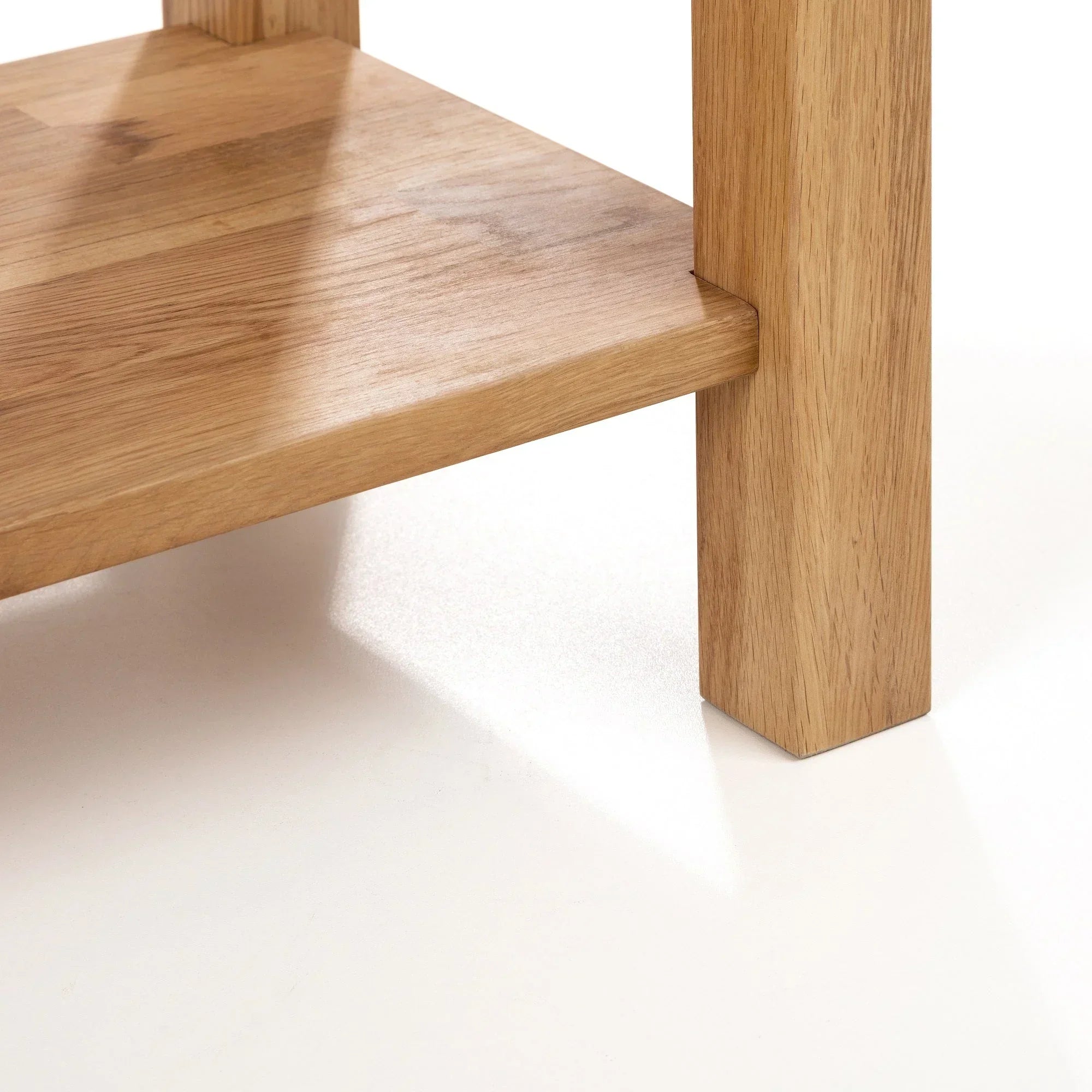 Oak console table leg and shelf detail on white background