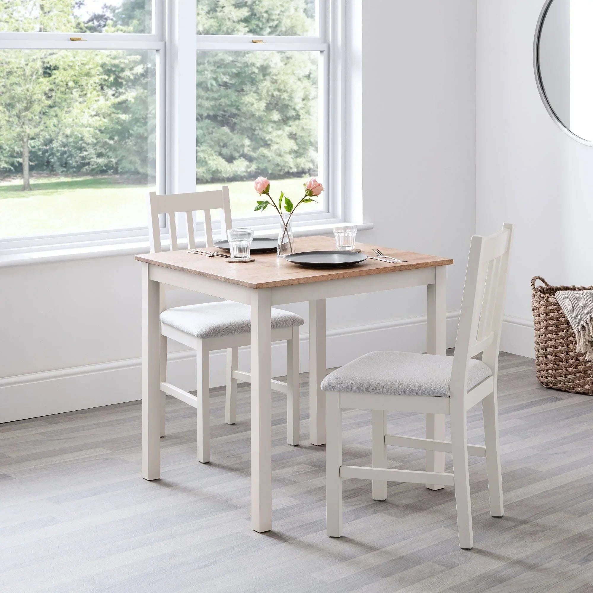 Square ivory oak dining table with two matching chairs in bright dining room