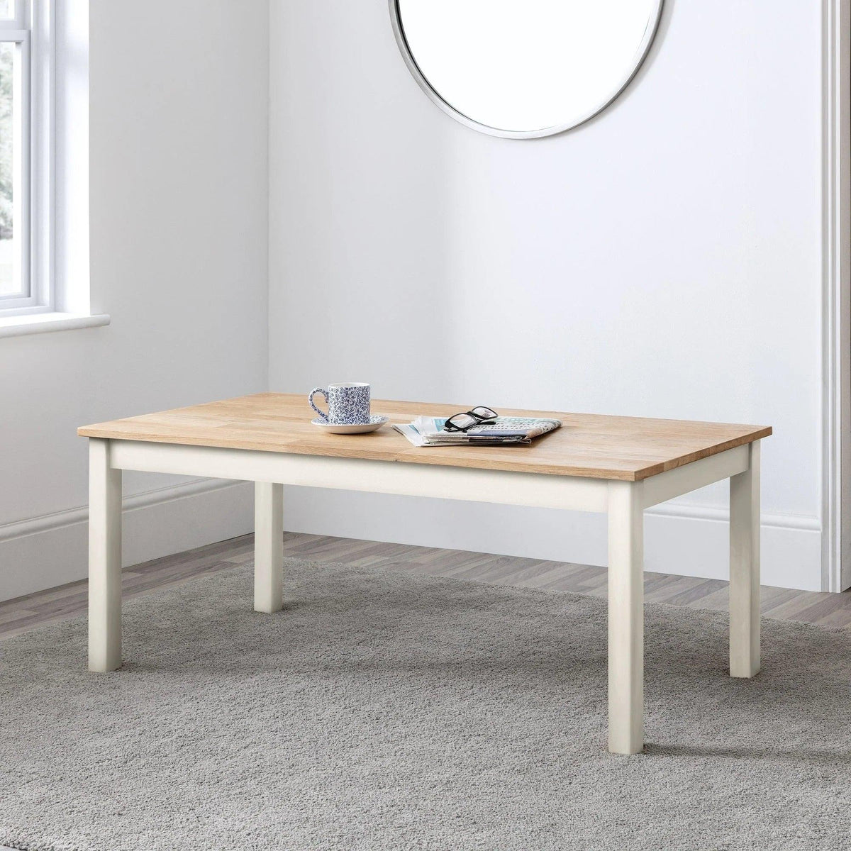 White and oak coffee table with cup, book, and glasses in modern living room setting