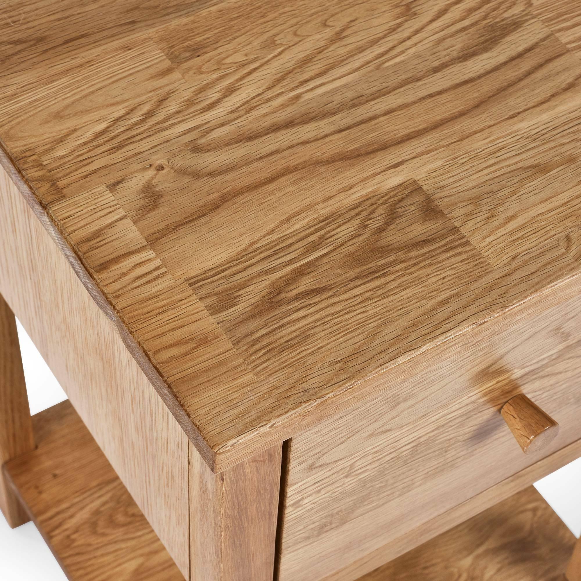 Solid oak bedside table with drawer and shelf, natural wood grain finish, top corner view