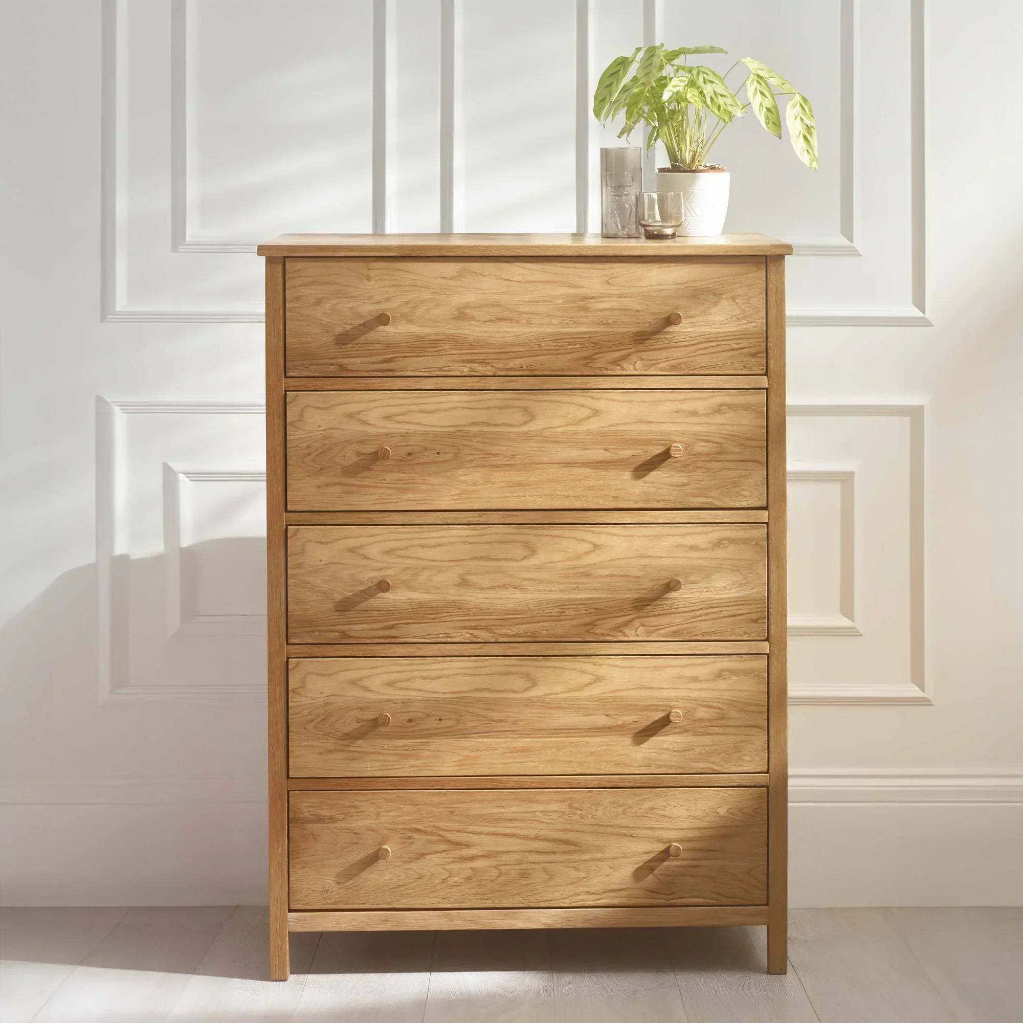 Oak chest of drawers with five drawers and round handles, potted plant on top