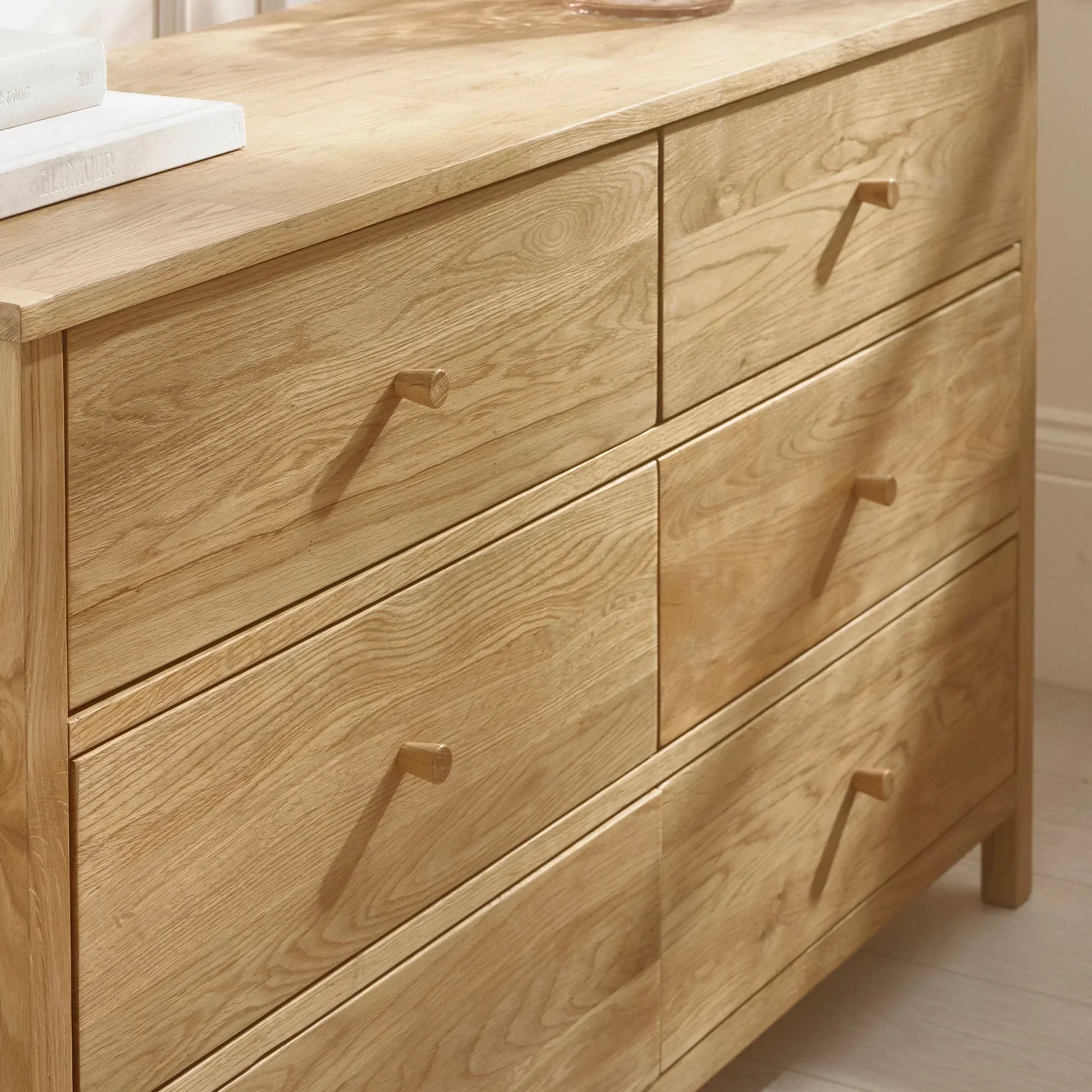 Oak six drawer chest with natural wood finish and simple handles in bedroom corner