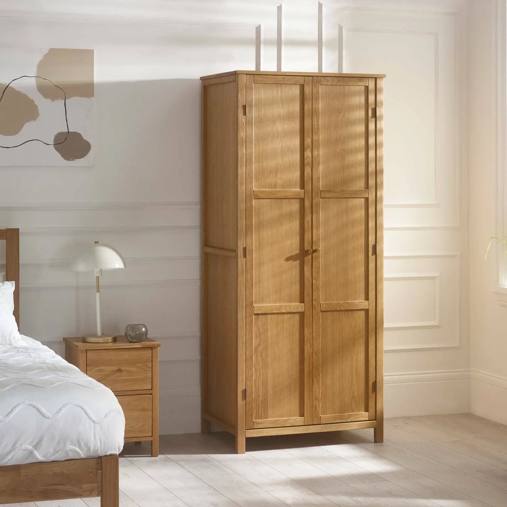Oak wardrobe with double doors in bright bedroom with wooden floor and matching nightstand