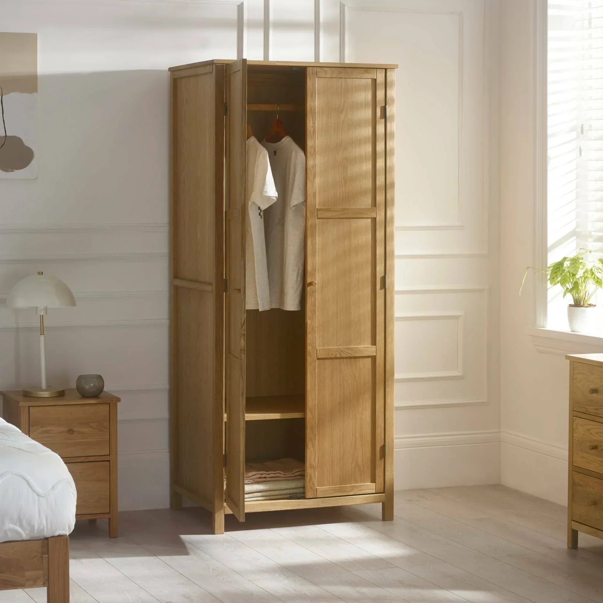 Oak wardrobe with open doors, hanging rail, and shelf in bright modern bedroom