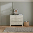Ivory three drawer chest with oak top in modern bedroom, decorated with vase and artwork