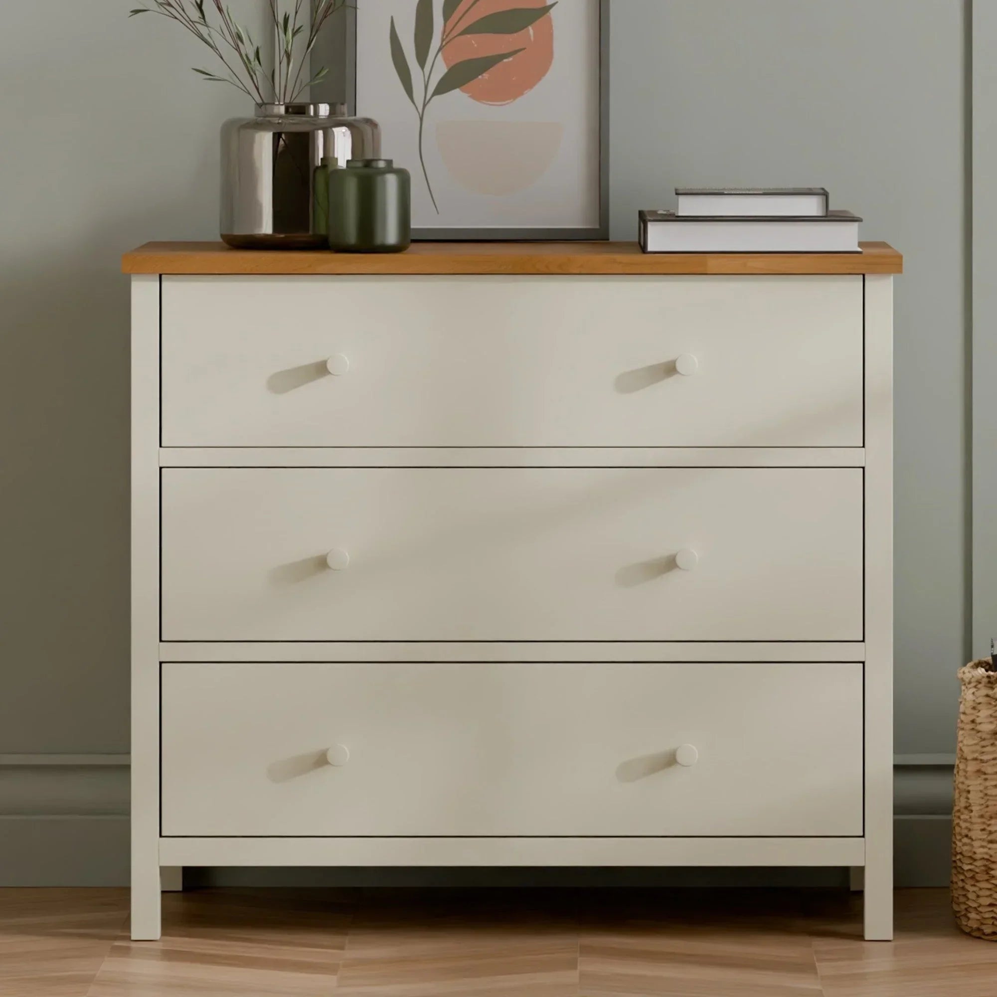 Cream three drawer chest of drawers with wooden top in modern bedroom setting