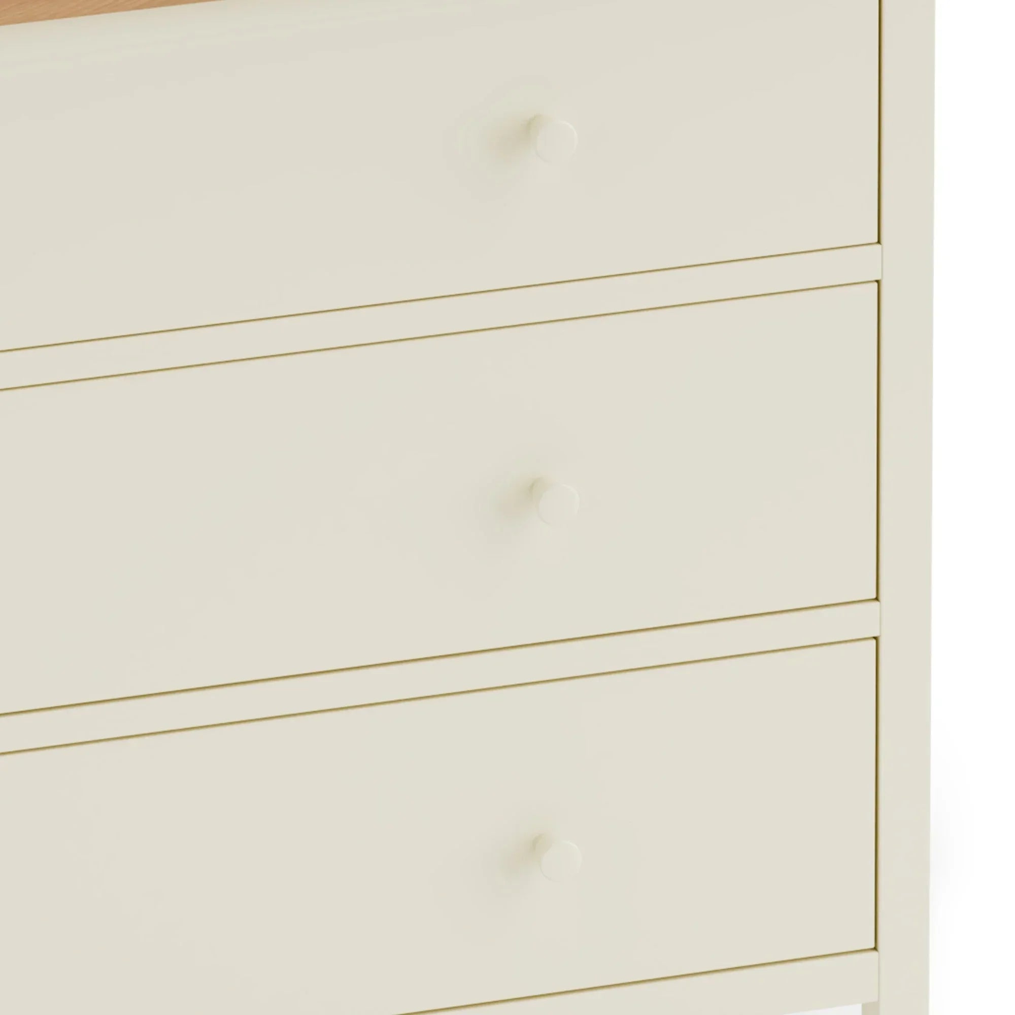 Cream chest of drawers with round knobs and wood effect top, close-up front view