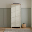 Ivory and oak wardrobe with double doors in a modern bedroom, top folded blanket, basket nearby