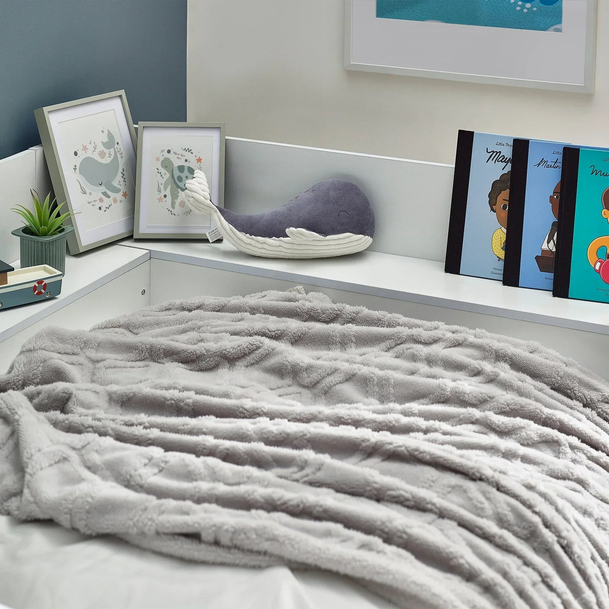 white cyclone daybed with plush grey throw, framed animal prints, books, and plant on shelf