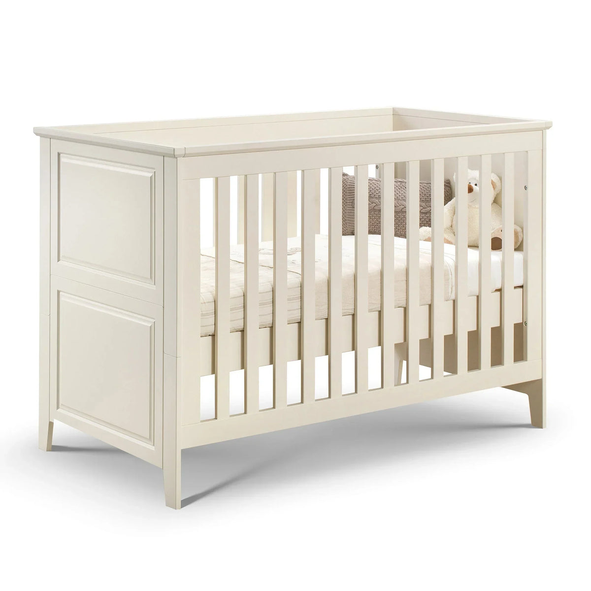 Cream wooden cot bed with panelled headboard, white mattress, and plush teddy bear