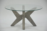 Round glass coffee table with grey marble effect cross base on white background