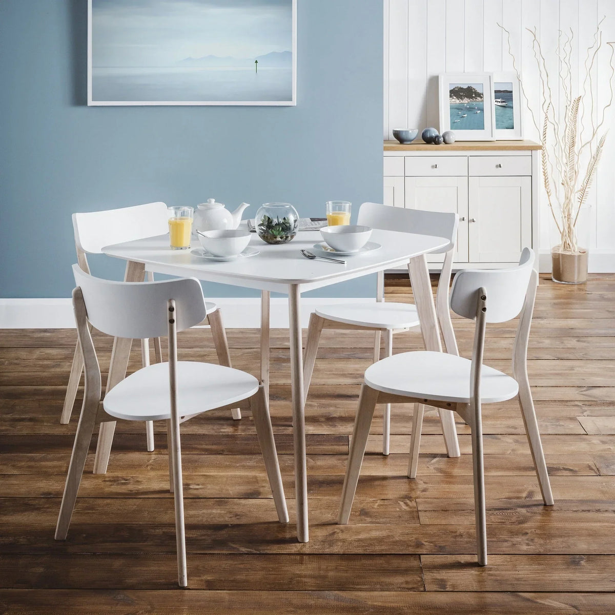 White dining room set with square table and four chairs on wooden floor