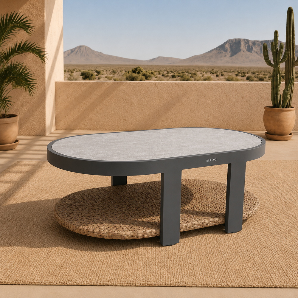Grey metal frame coffee table with white stone top and rattan shelf under sunlight