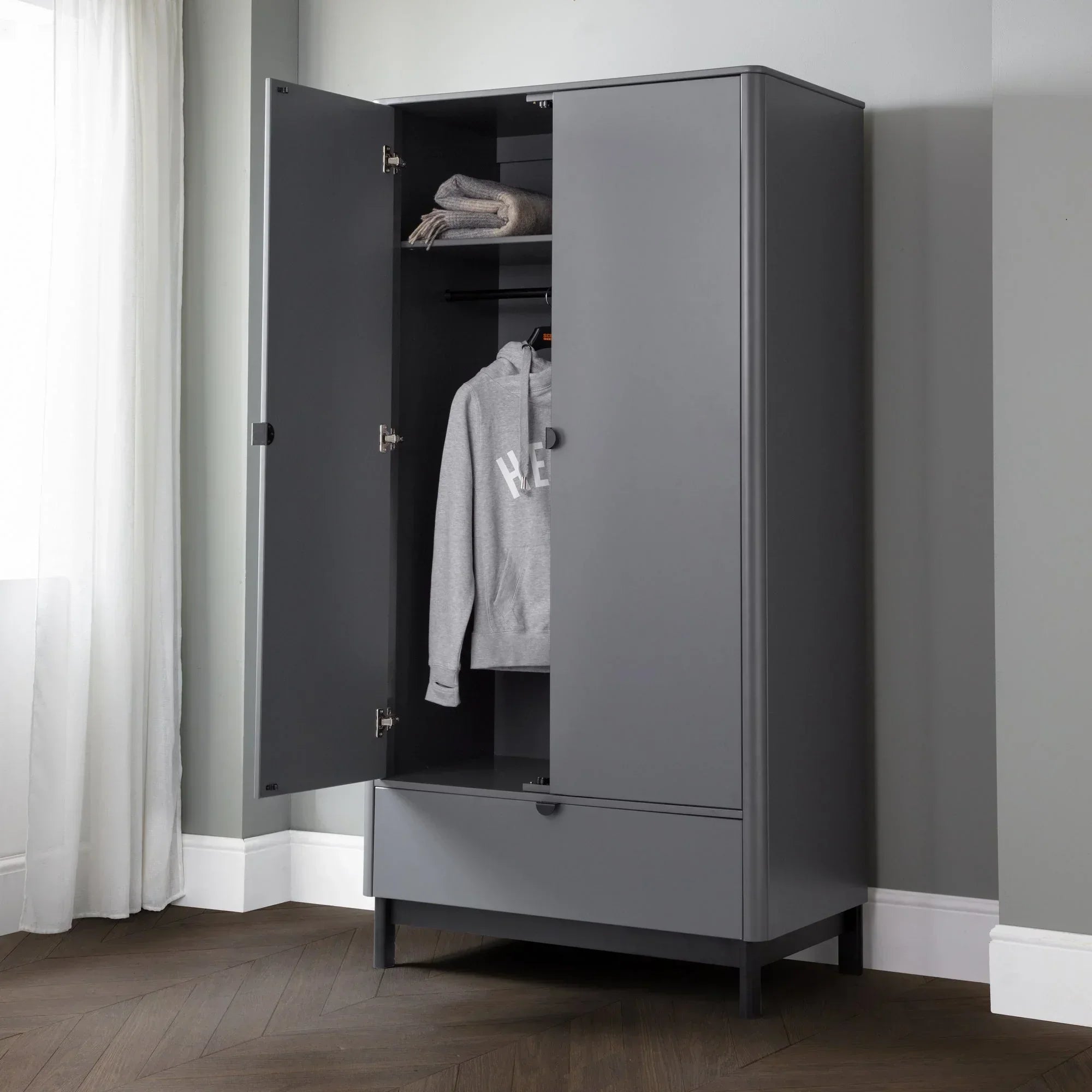 Grey wardrobe with open doors, shelving, hanging rail and lower drawer in modern room