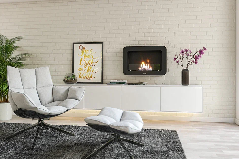 Modern lounge chair and footstool with light fabric beside wall mounted cabinet and fireplace