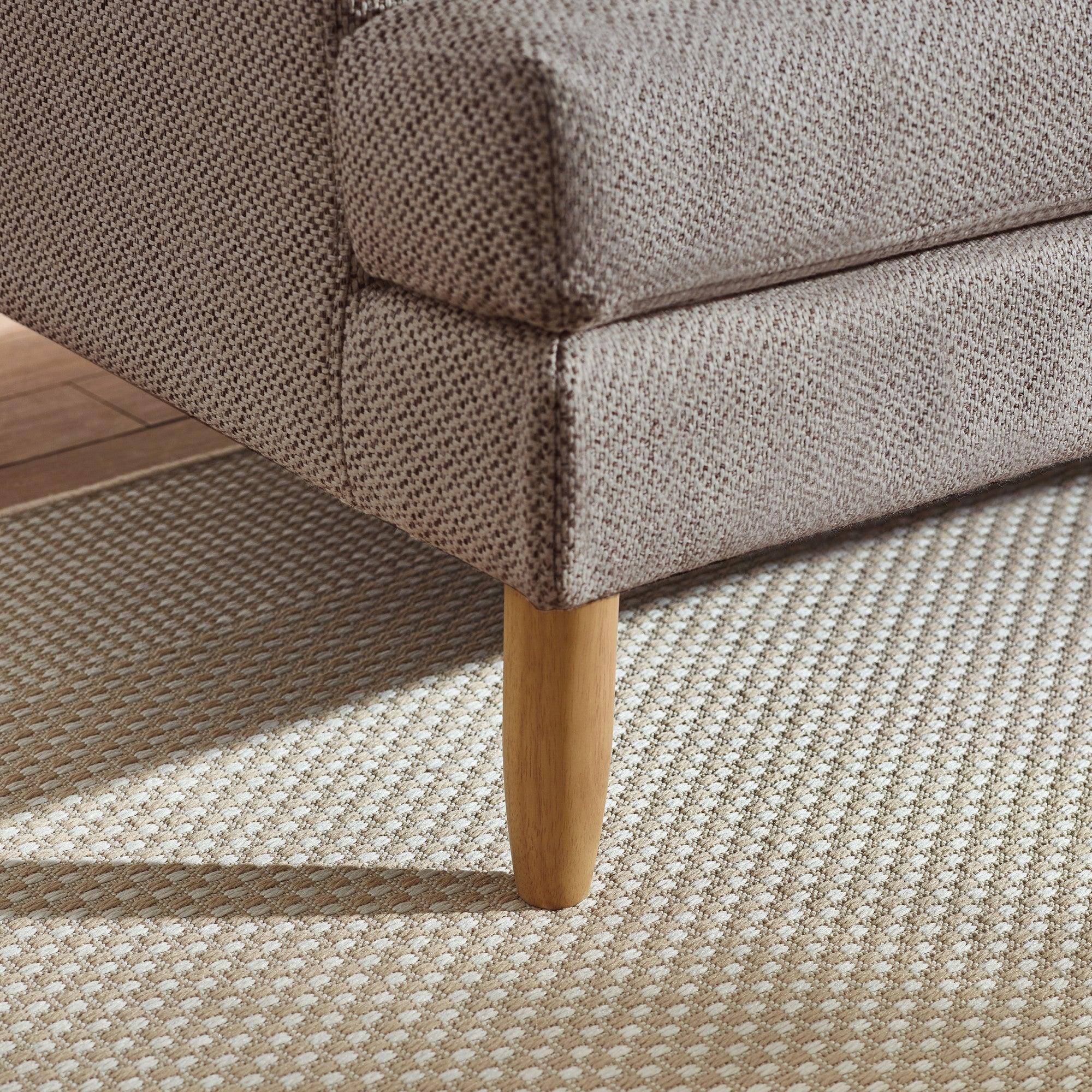 Textured fabric sofa corner with wooden leg on patterned beige rug