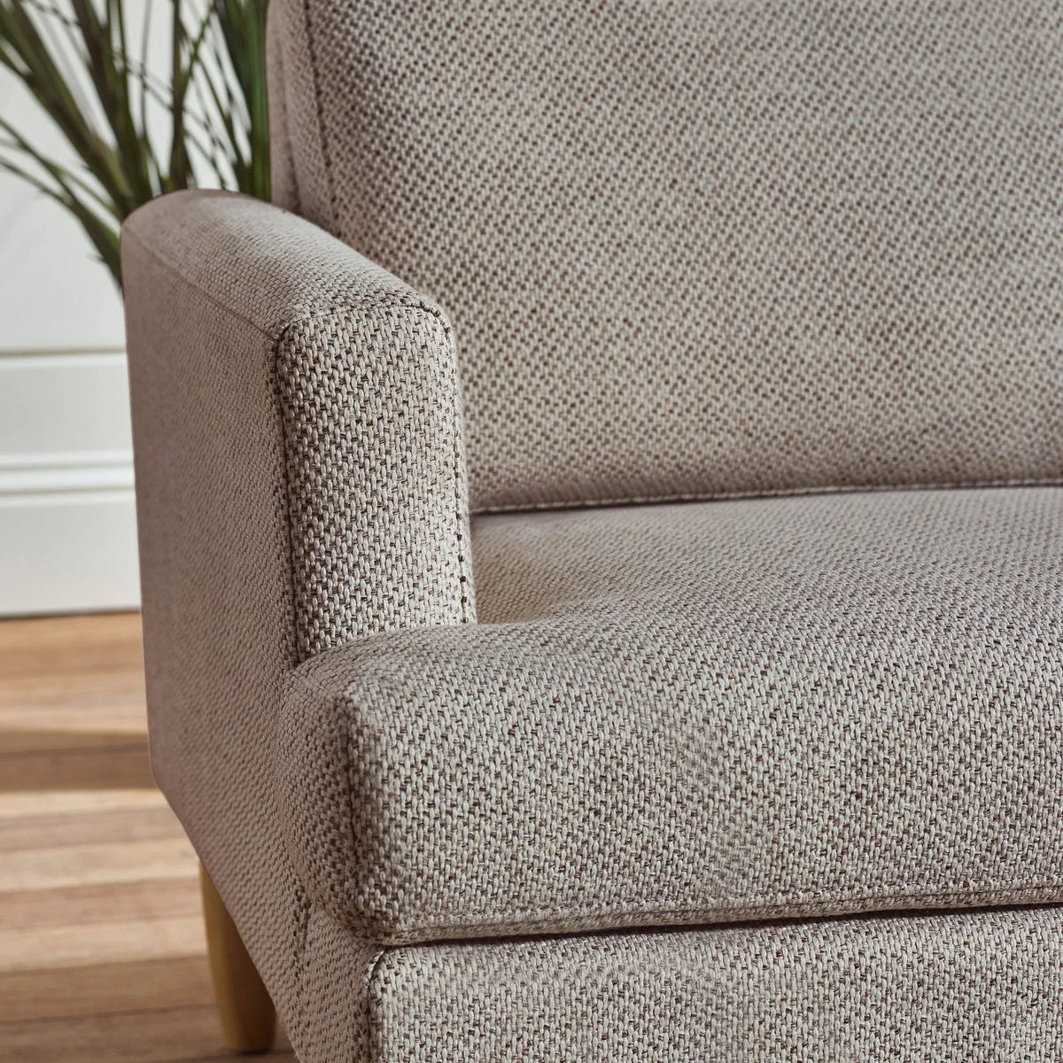 Close-up of beige fabric sofa armrest and seat with textured upholstery