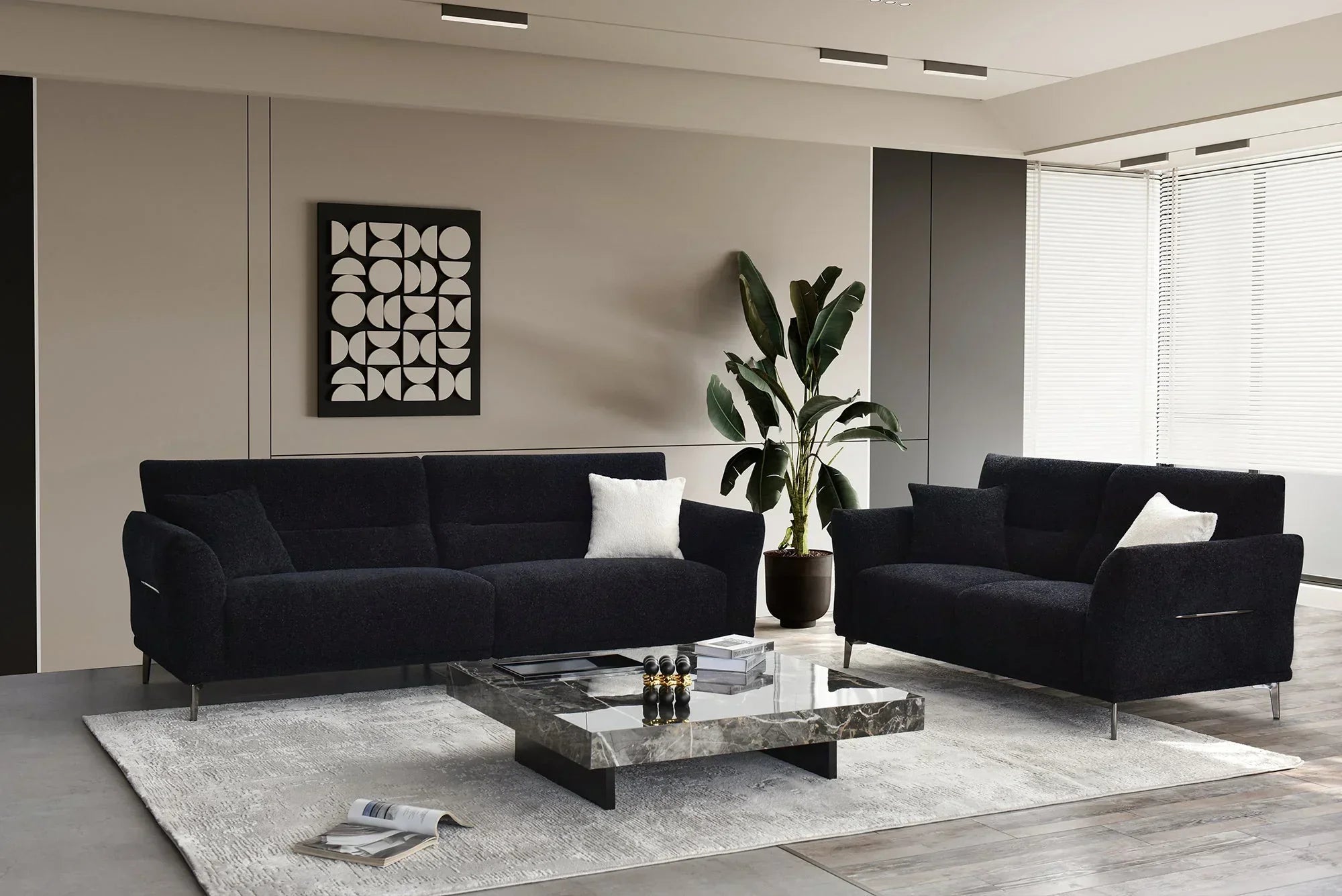 Modern living room with black fabric sofas, marble coffee table, and indoor plant on rug
