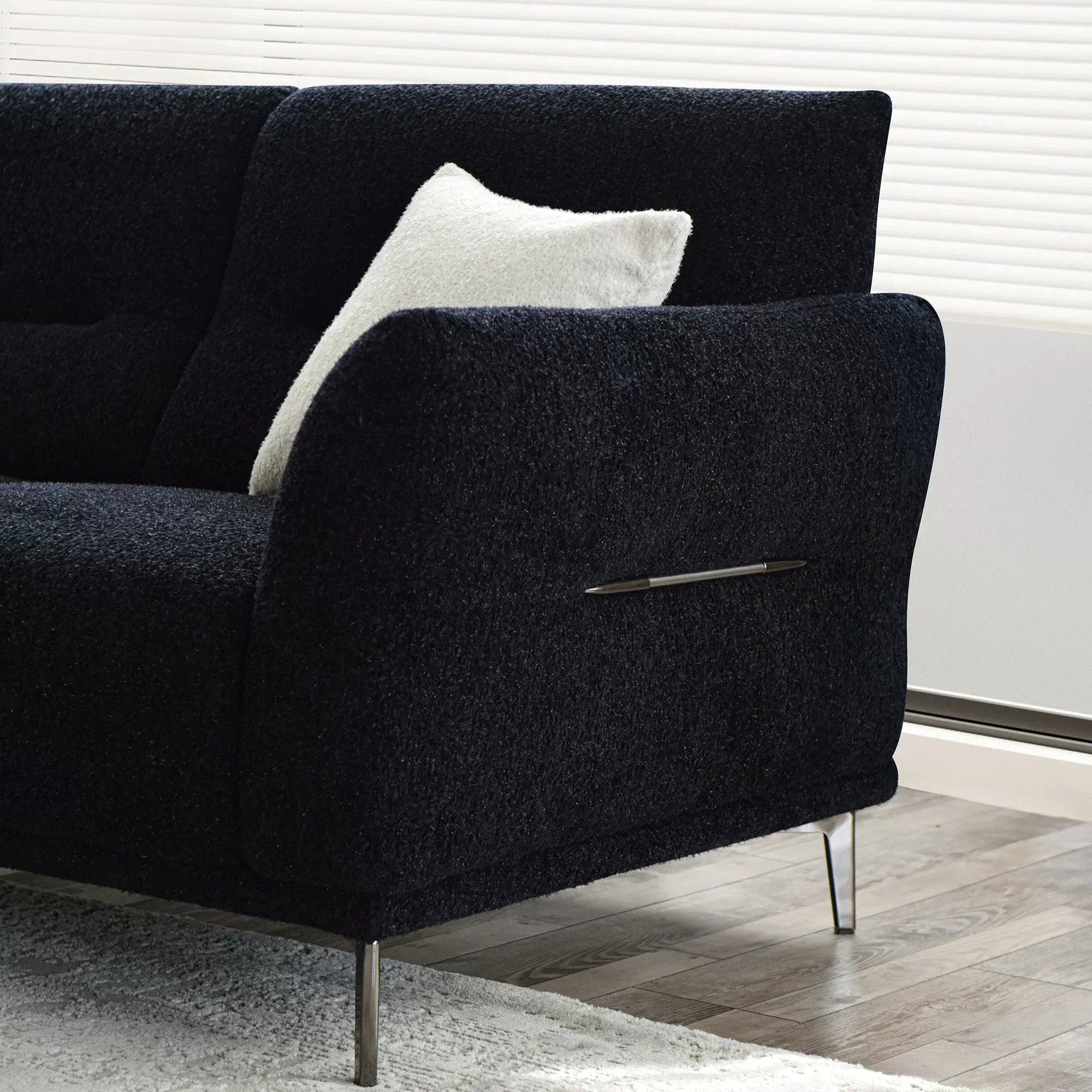 Black textured fabric sofa with chrome legs and a white cushion in modern living room