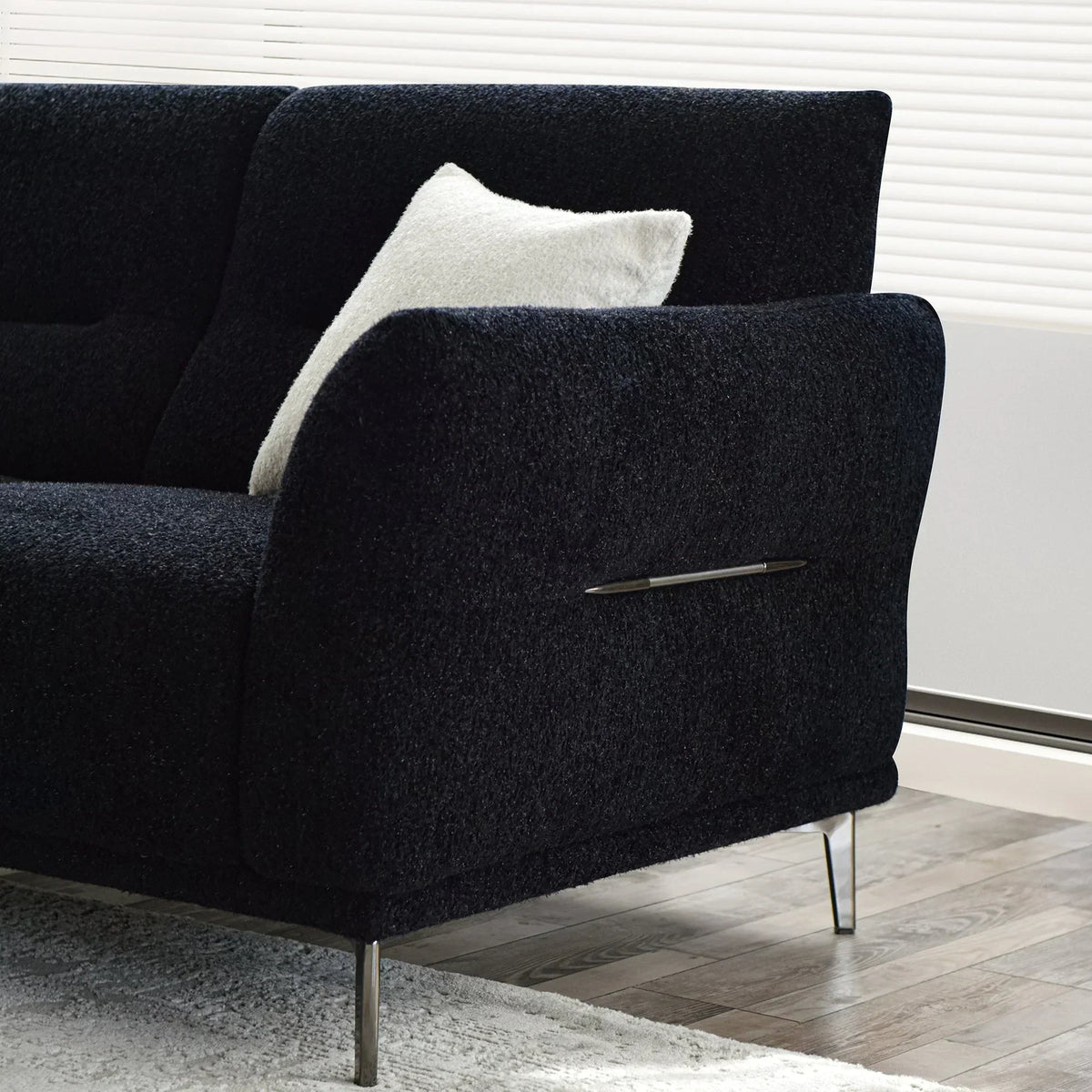 Black textured fabric sofa with chrome legs and a white cushion in modern living room