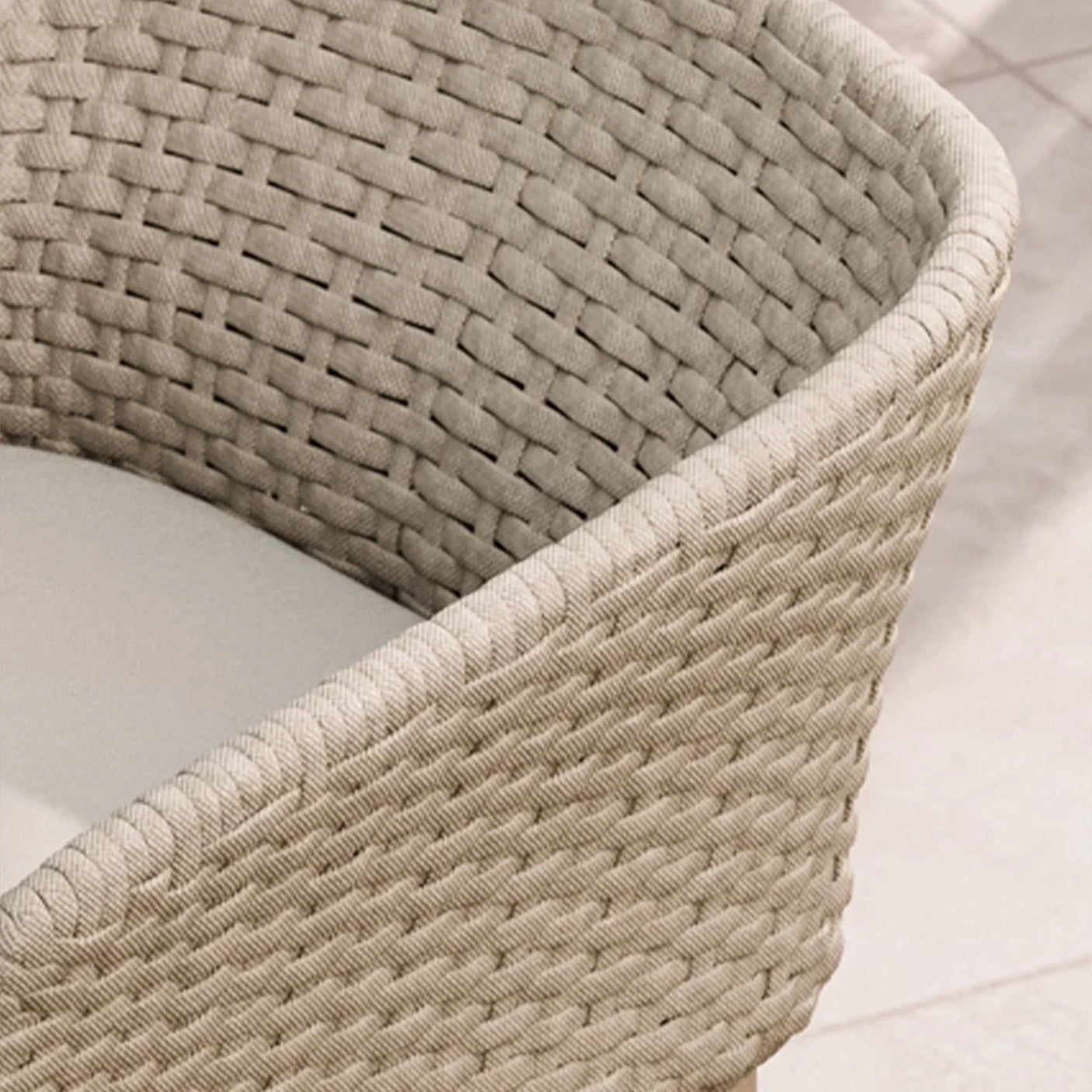 Close detail of woven rattan dining chair with curved backrest and cushioned seat