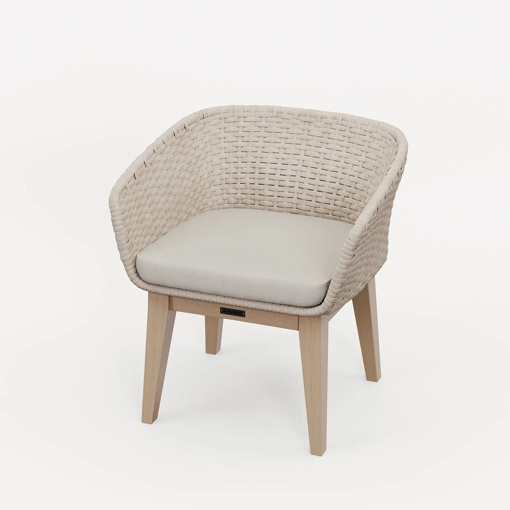 Beige rattan accent chair with light wood legs and cushioned seat on white background