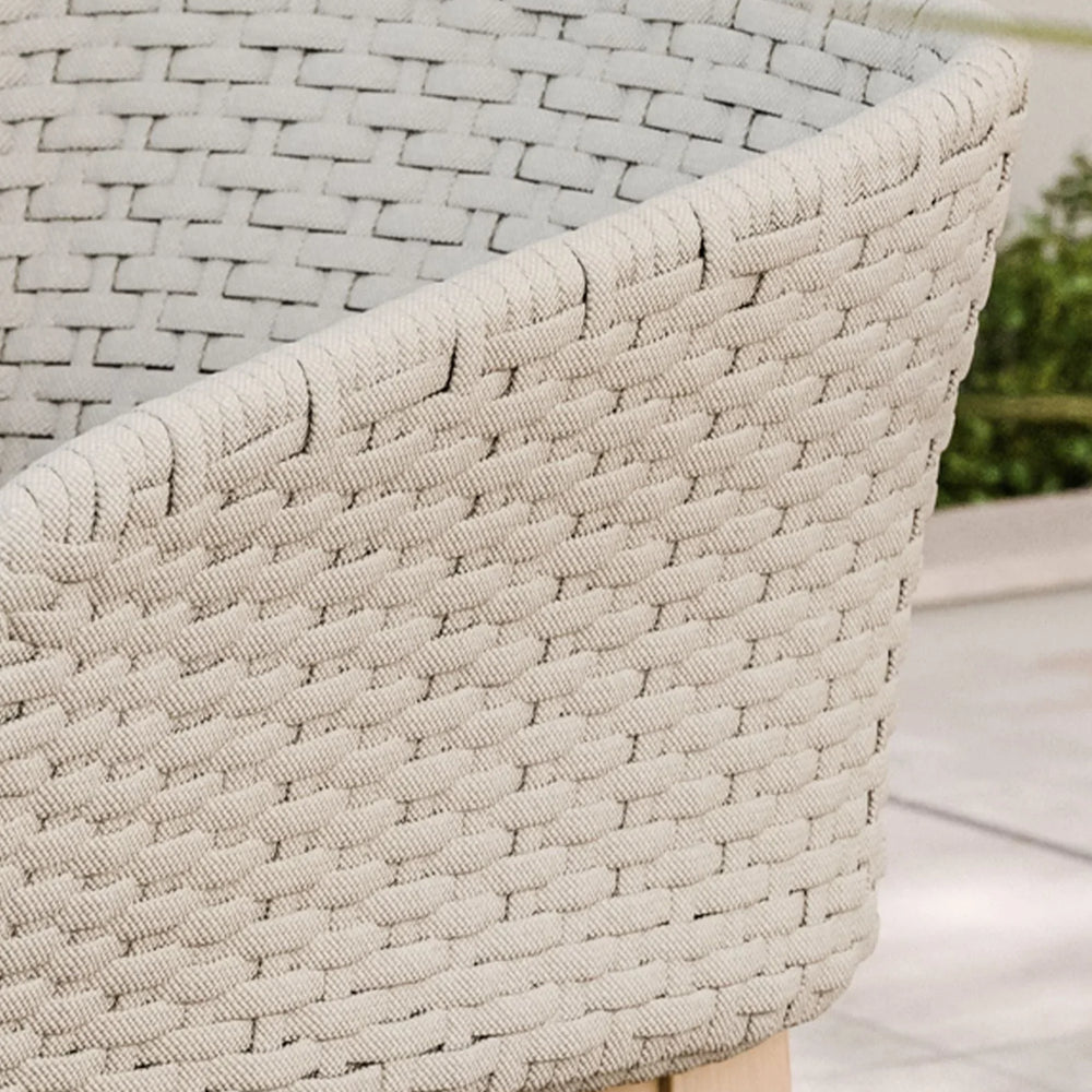 Beige woven armchair with wooden legs on outdoor patio