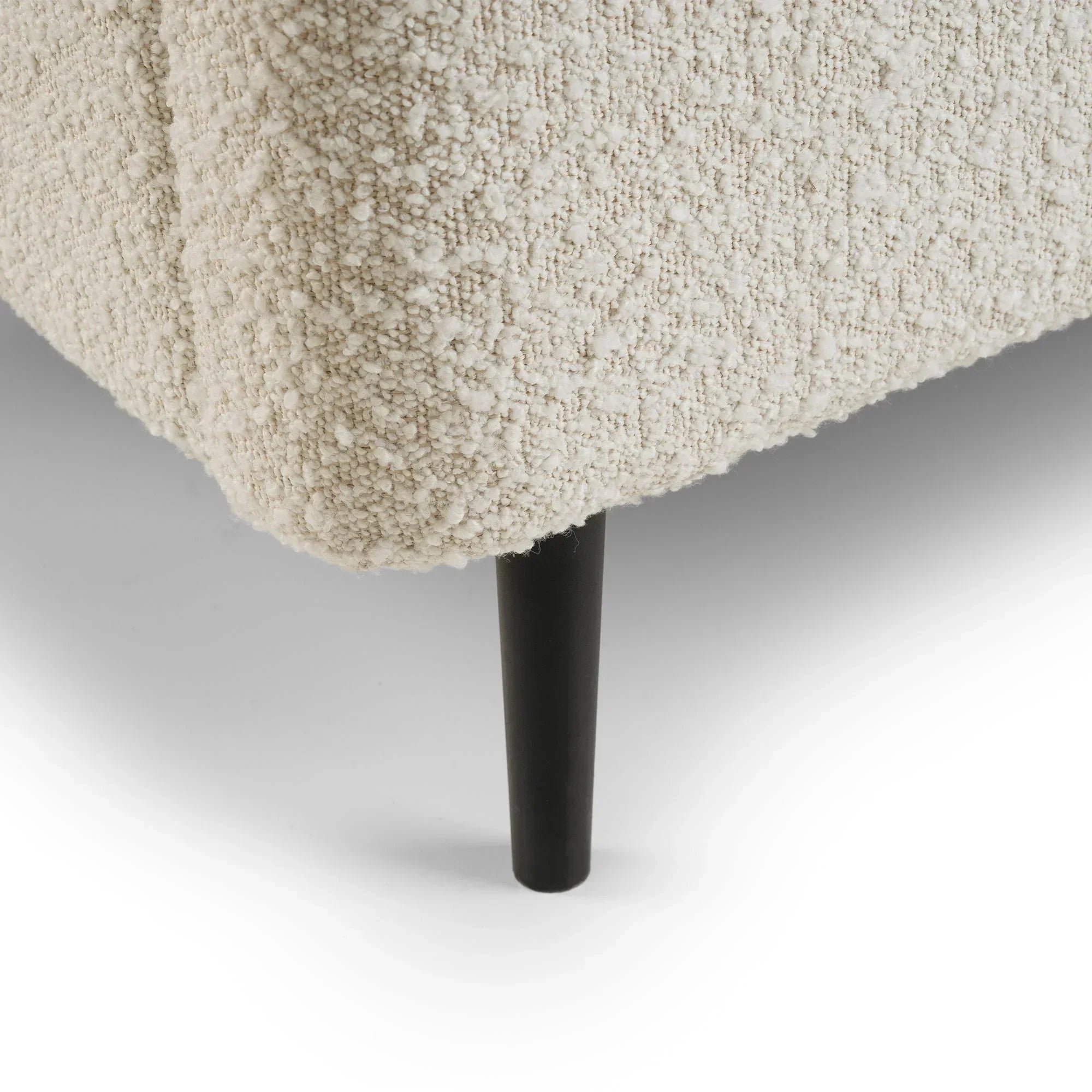 Ivory boucle bed base corner with textured fabric and black tapered leg detail