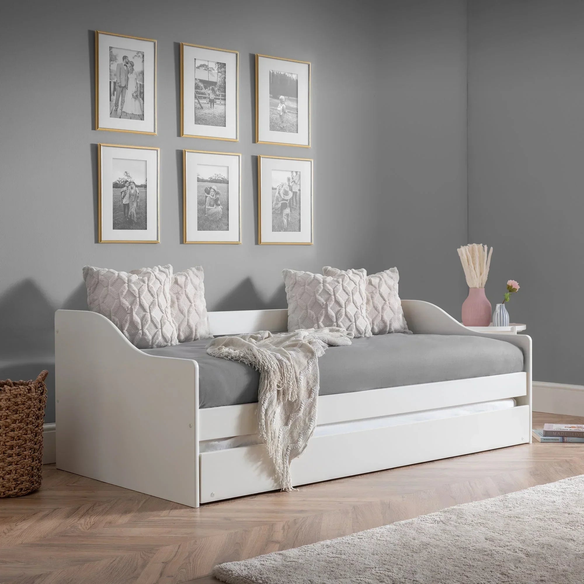 White single daybed with grey mattress, decorative pillows, and throw in modern room setting