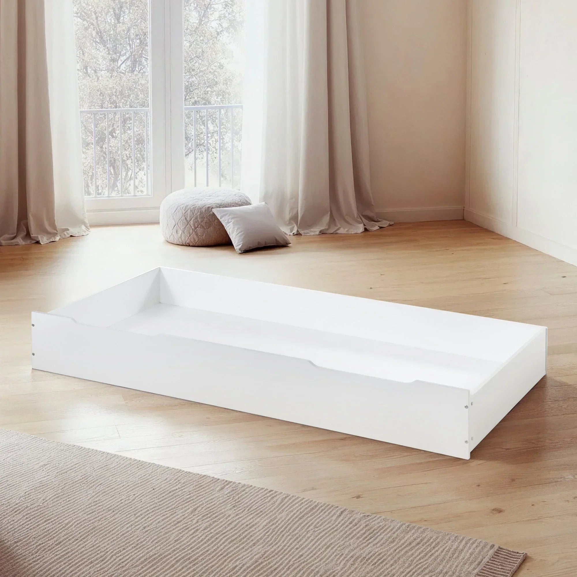 White wooden underbed storage drawer on wooden floor in bright bedroom