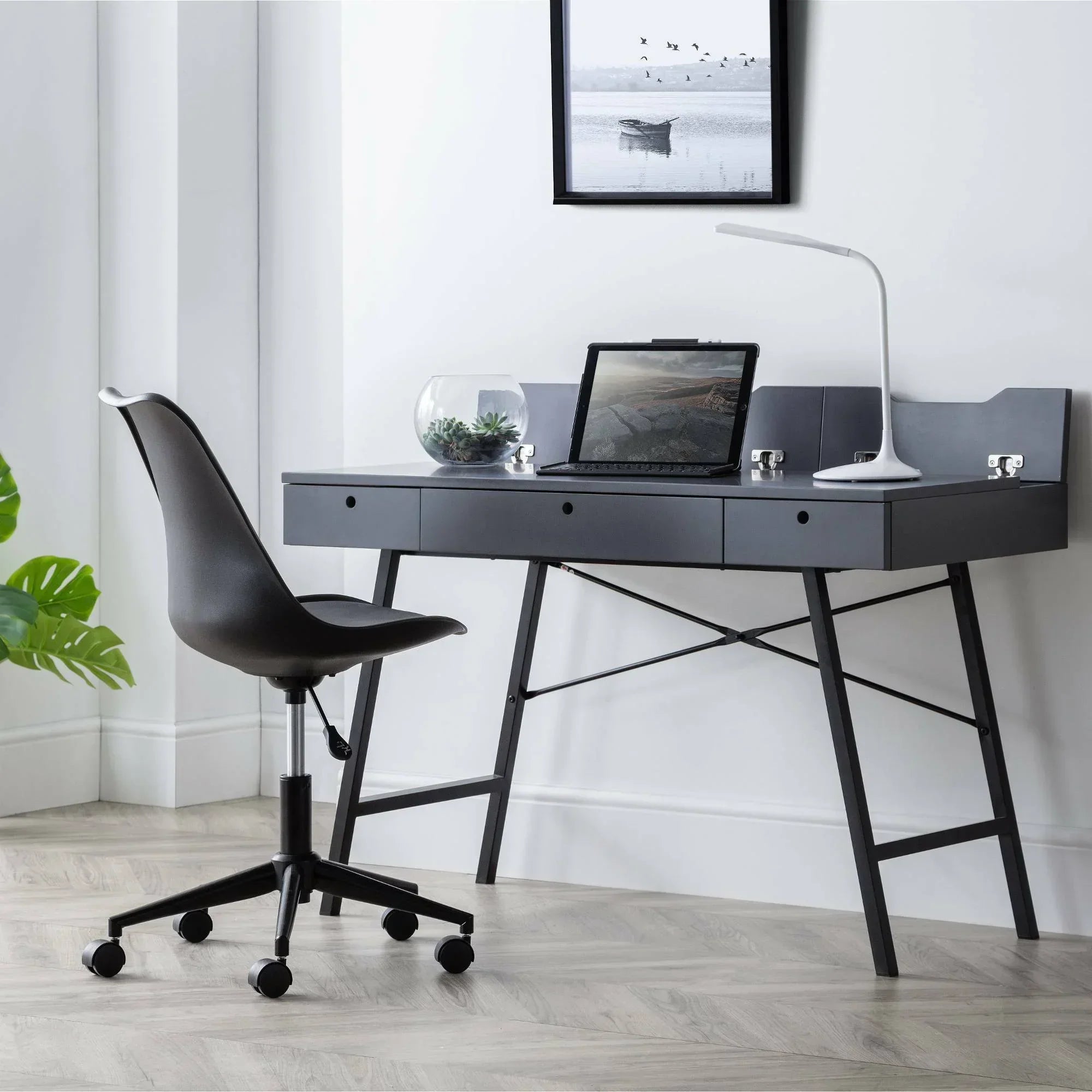 Black ergonomic office chair on casters beside modern desk in home workspace