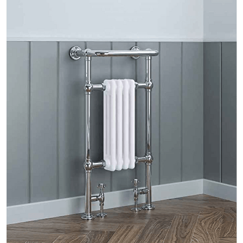 Chrome towel radiator with a white towel against a gray paneled wall.