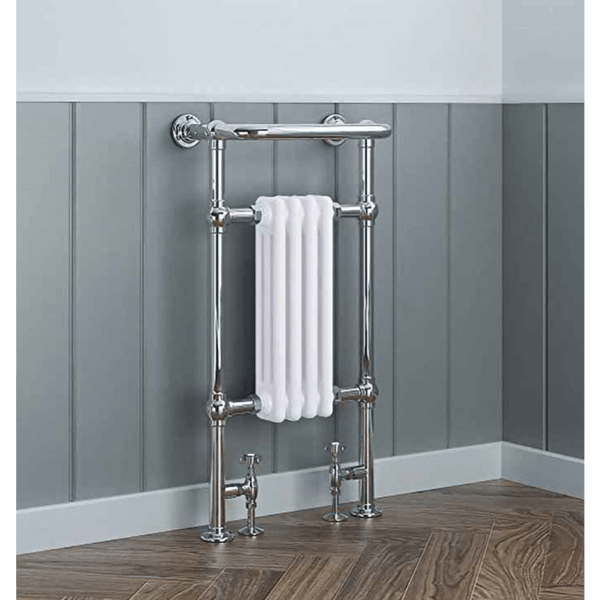 Chrome towel radiator with a white towel against a gray paneled wall.
