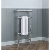 Chrome towel radiator with a white towel against a gray paneled wall.