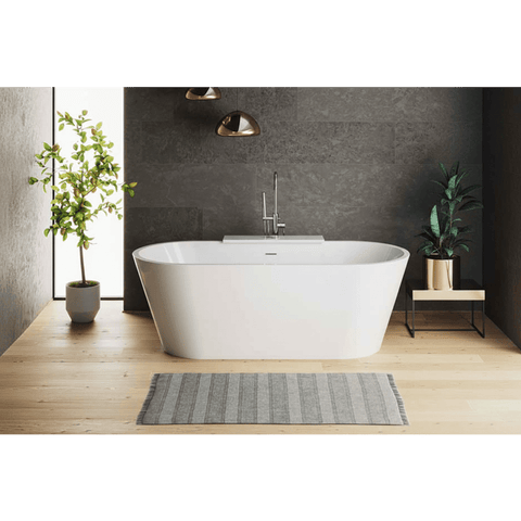 Modern bathroom with a freestanding bathtub, plants, and a gray wall.
