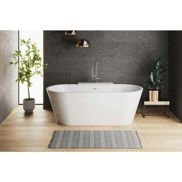 Modern bathroom with a freestanding bathtub, plants, and a gray wall.