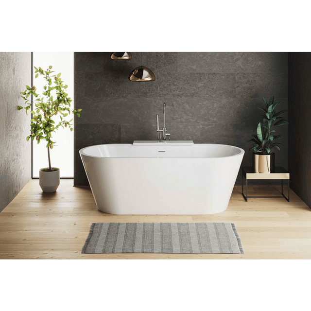 Modern bathroom with a freestanding bathtub, plants, and a gray wall.