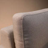 Close view of light beige fabric corner sofa armrest and cushion upholstery