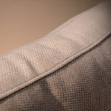 Closeup of sofa backrest showing textured light beige fabric and stitching detail