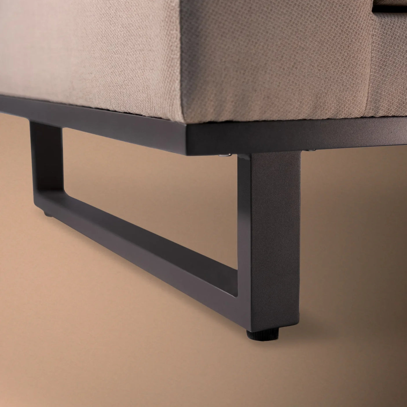 Close-up of corner sofa metal leg with beige fabric upholstery