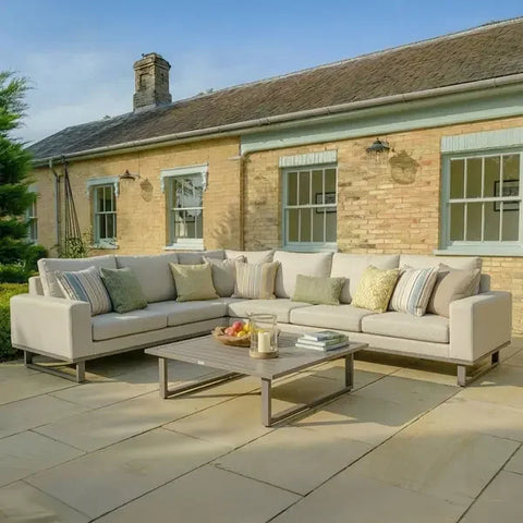 Large corner fabric sofa in latte color with cushions on outdoor patio, rectangle coffee table
