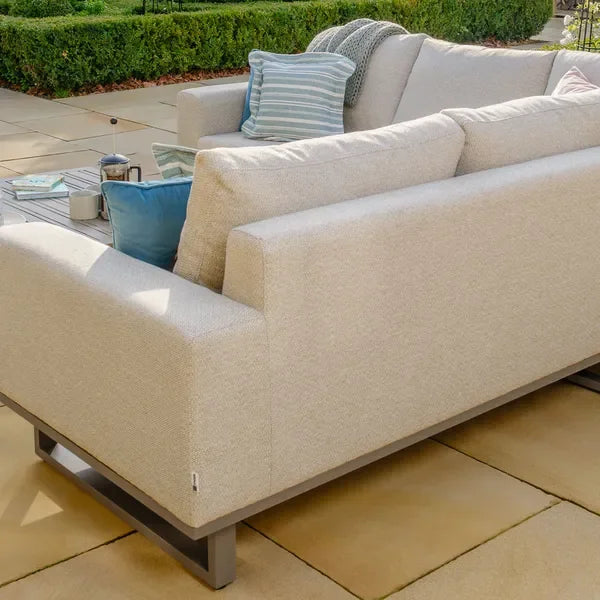 Large corner sofa in latte fabric with metal base on patio, scatter cushions and coffee table