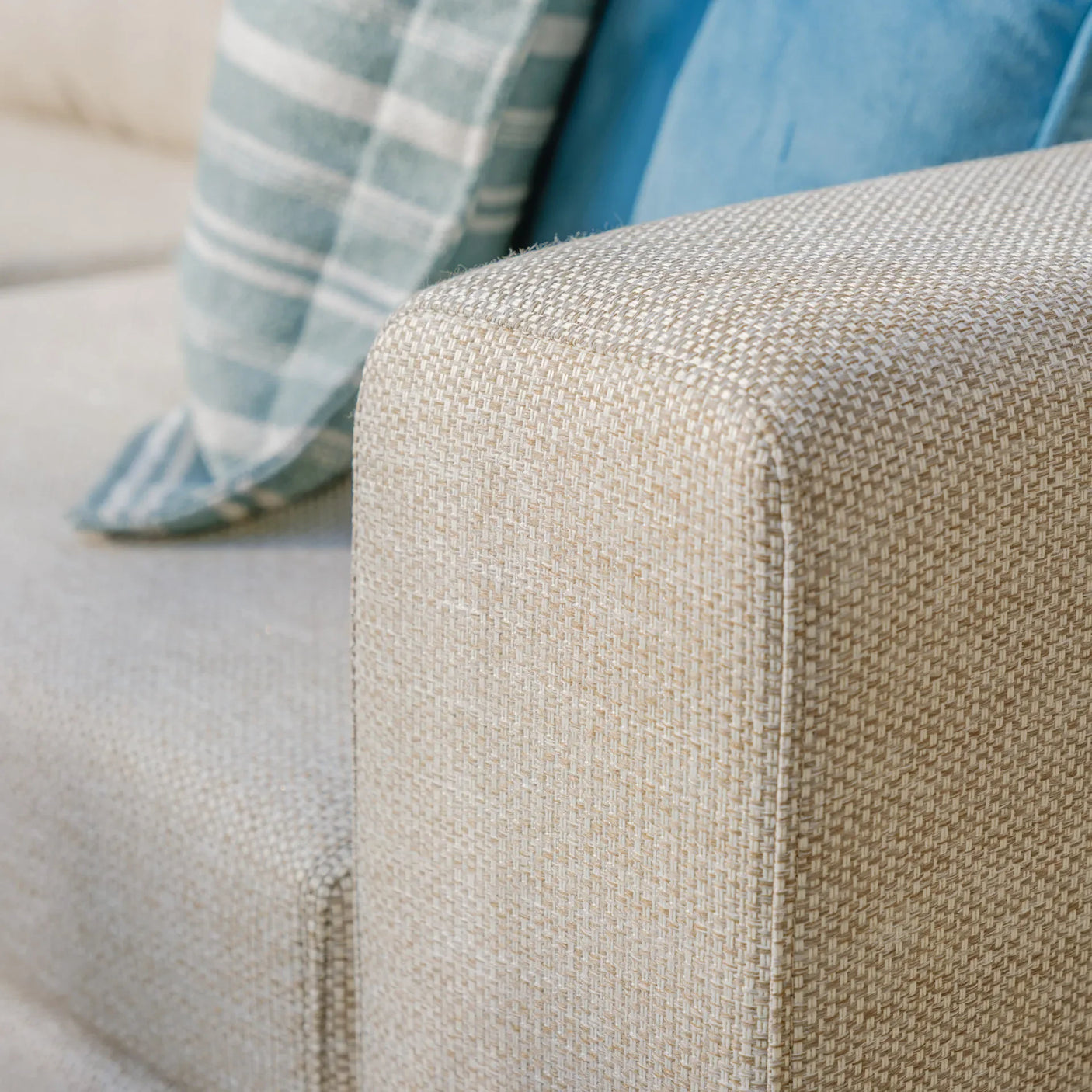 Latte fabric corner sofa armrest detail with blue and striped cushions