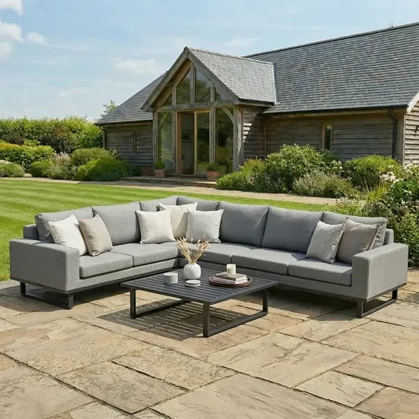 Large grey corner garden sofa set with cushions and coffee table on stone patio