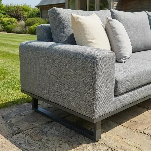 Grey corner group sofa with metal legs and neutral cushions on stone patio outdoors