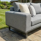 Grey corner group sofa with metal legs and neutral cushions on stone patio outdoors