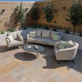 Modern outdoor sofa set with light grey cushions and armchairs on a stone patio