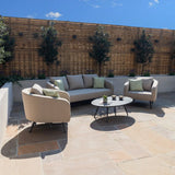 Outdoor beige fabric sofa set with armchairs and round coffee table on patio