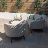 Beige outdoor sofa set with round armchair, coffee table and patterned cushions on patio
