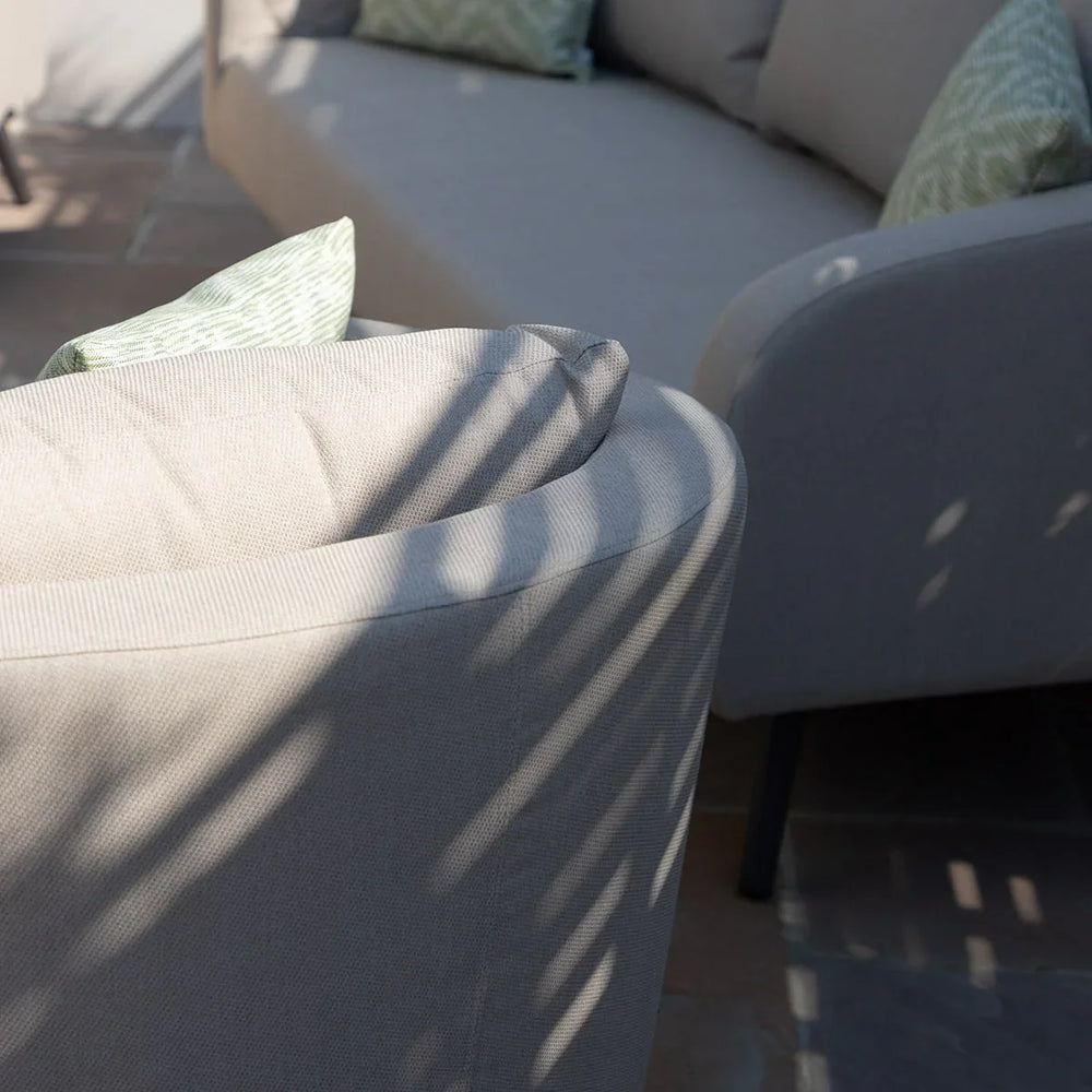 Light grey outdoor sofa set with green patterned cushions in sunlight